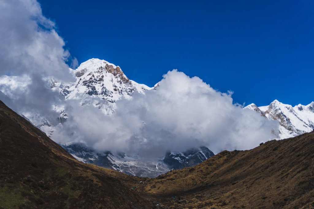 pexels-photo-26570336 Spectacular view of snow-capped Machhapuchchhre peak surrounded by clouds in Nepal.